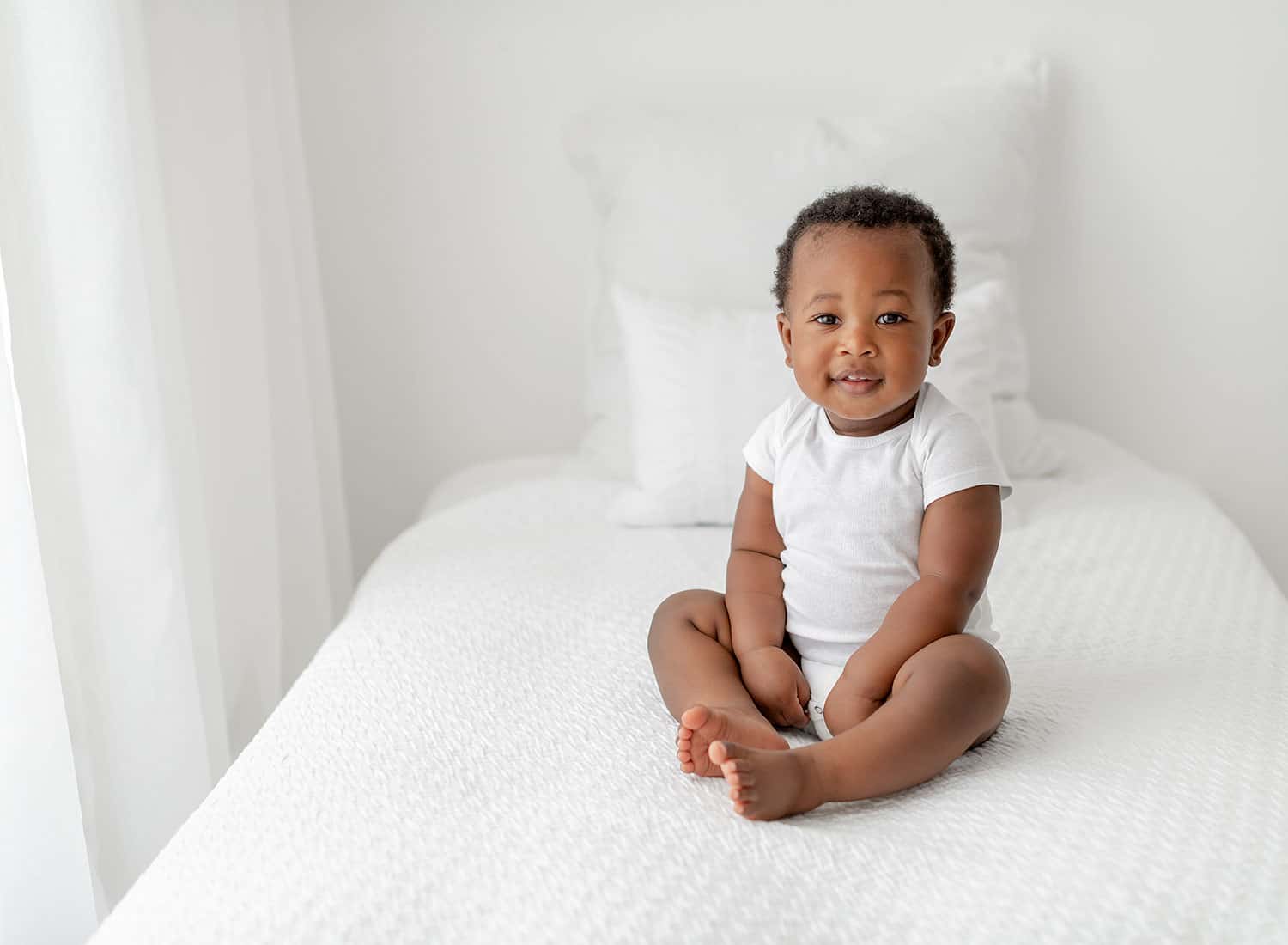 30a babysitting baby on white bed by Andrea Krey Photography