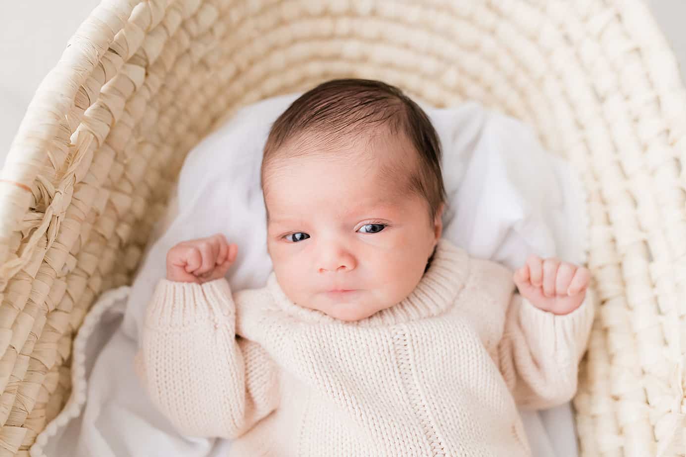 A baby boy is peacefully resting in a wicker basket.