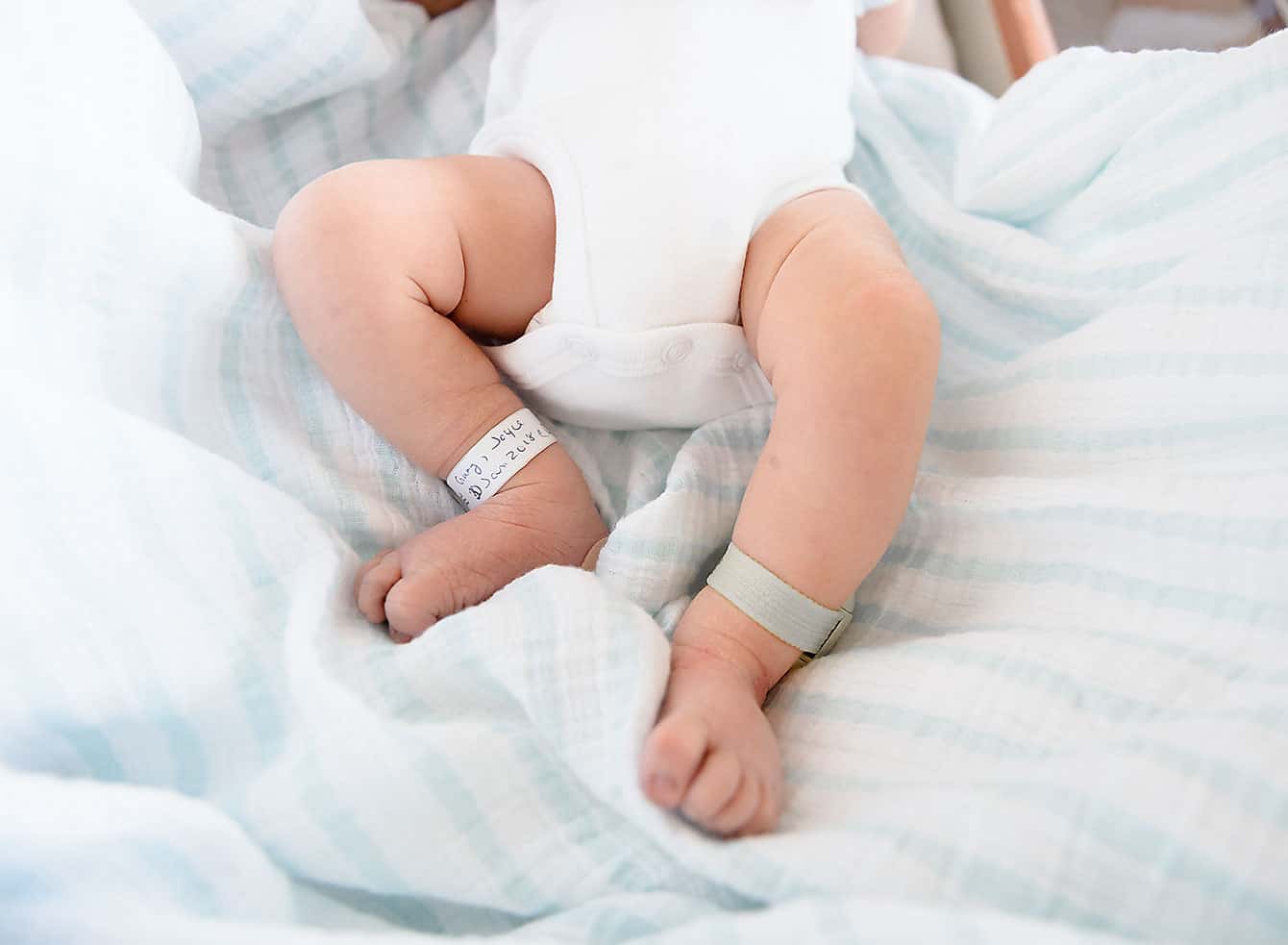 A newborn infant on a bed with a blue blanket captured through Fresh48 photography in Destin FL.