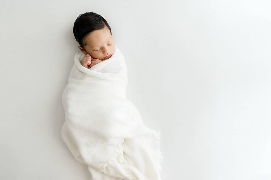 sleeping newborn wrapped in organic white wrap