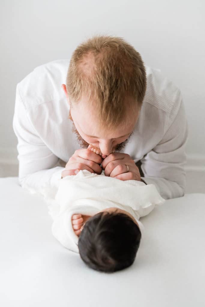 a father kissing baby toes