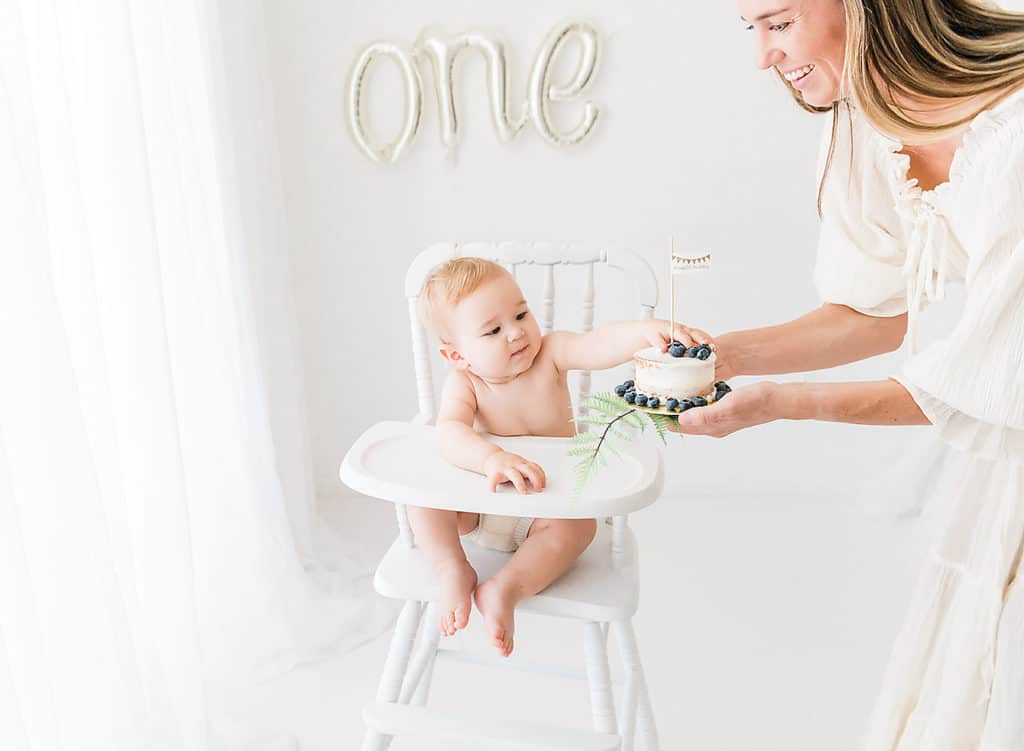 a mom handing her one year old his smash cake