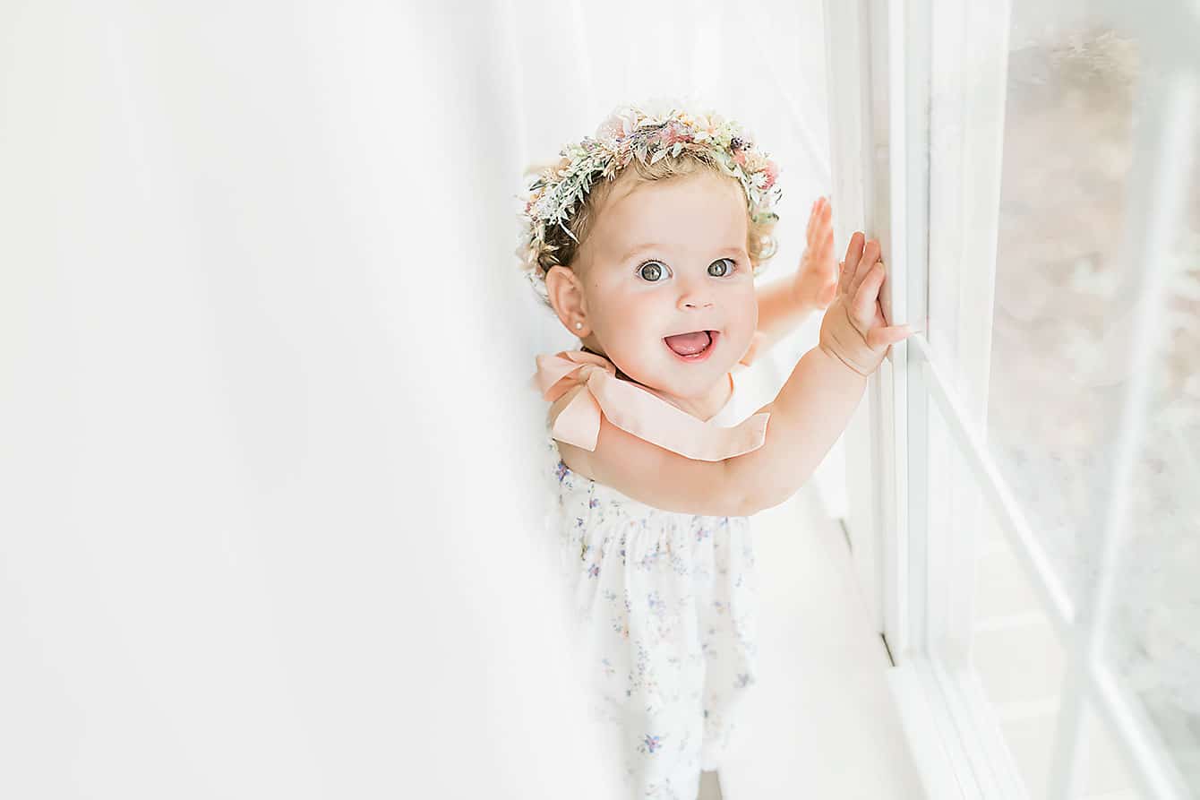 smiling baby standing by a window