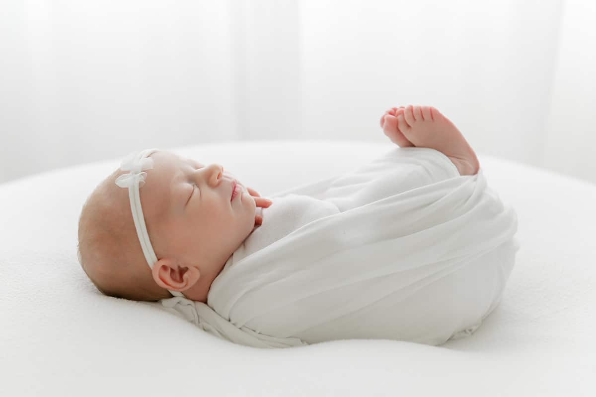 4D ultrasound Pensacola &mdash; newborn baby girl swaddled in white at Andrea Krey Photography studio in Niceville