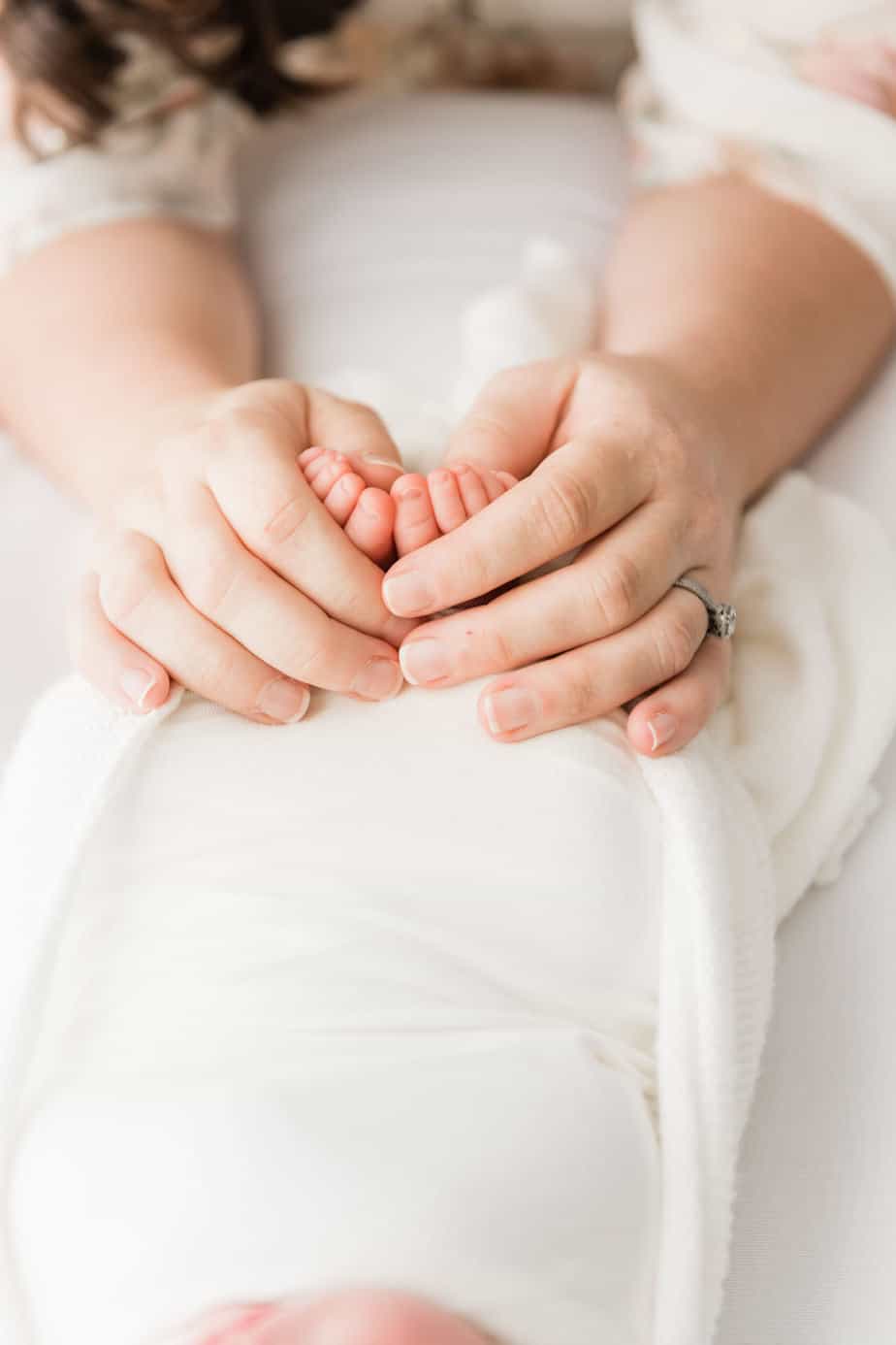 moms hands on newborns feet detail shot