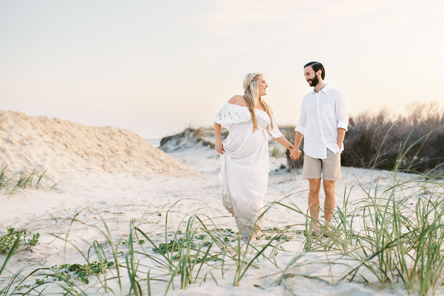 happy pregnant couple walking on 30a beach