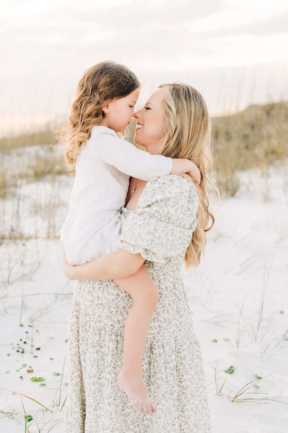 pregnant woman and her daughter giving eskimo kisses at the beach