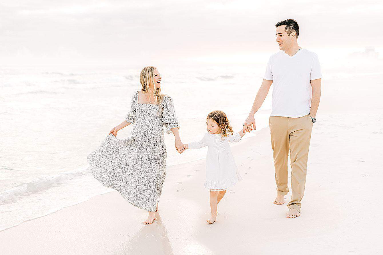 a happy family walking along the beach during their Florida babymoon