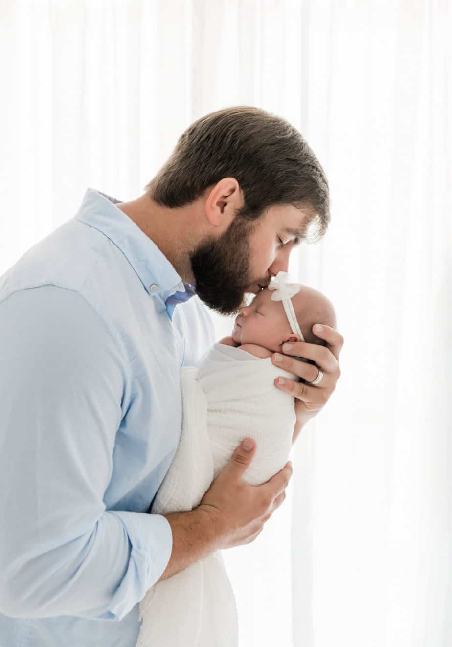 a father holding his newborn baby girl and kissing