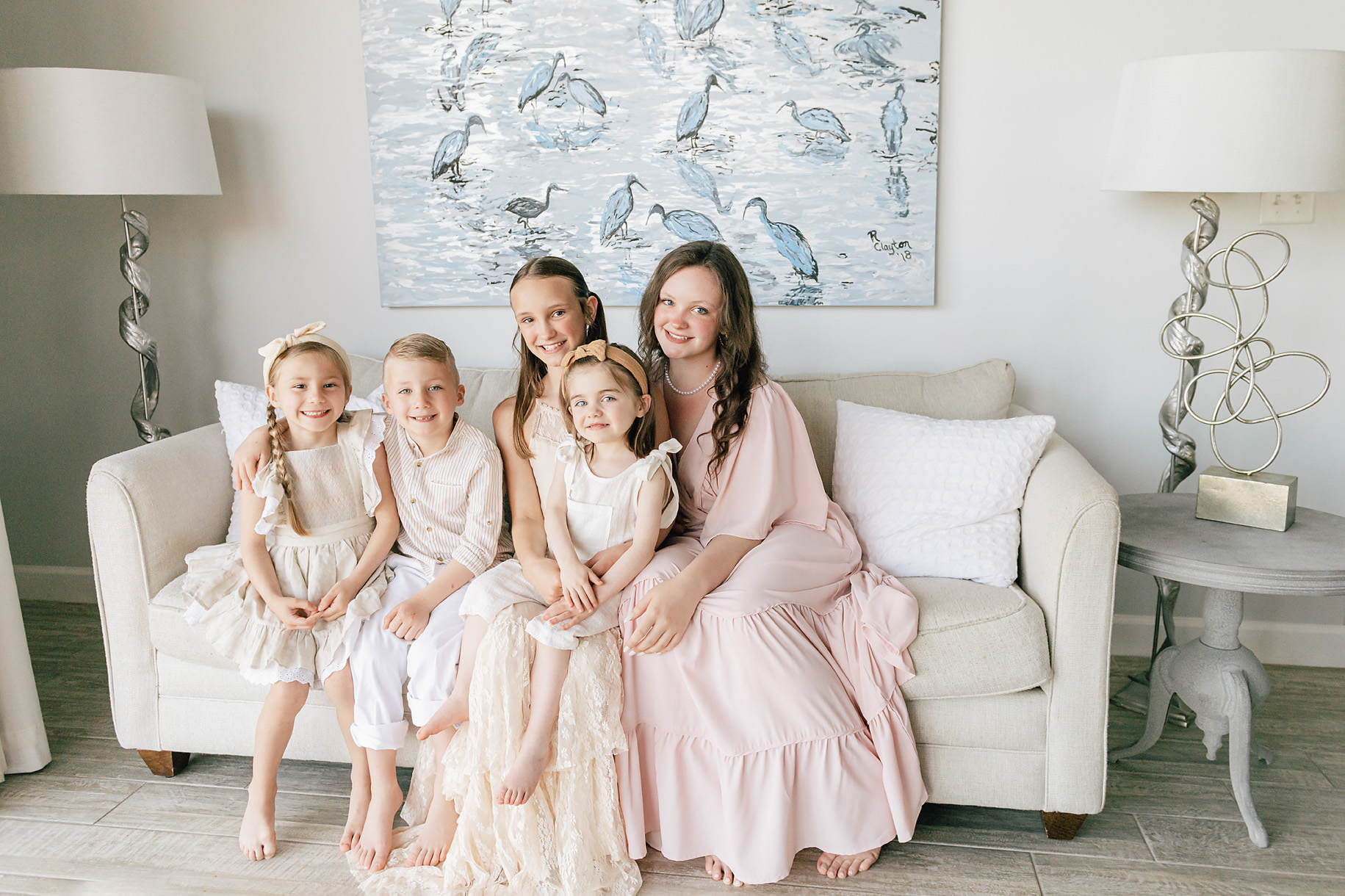 kids dressed in warm and neutral colors sitting in front of a beautiful picture
