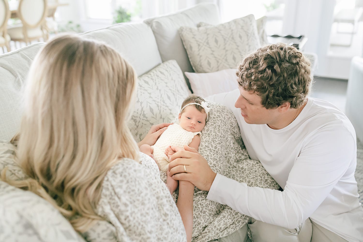 new parents admiring their newborn baby girl when sitting on their couch