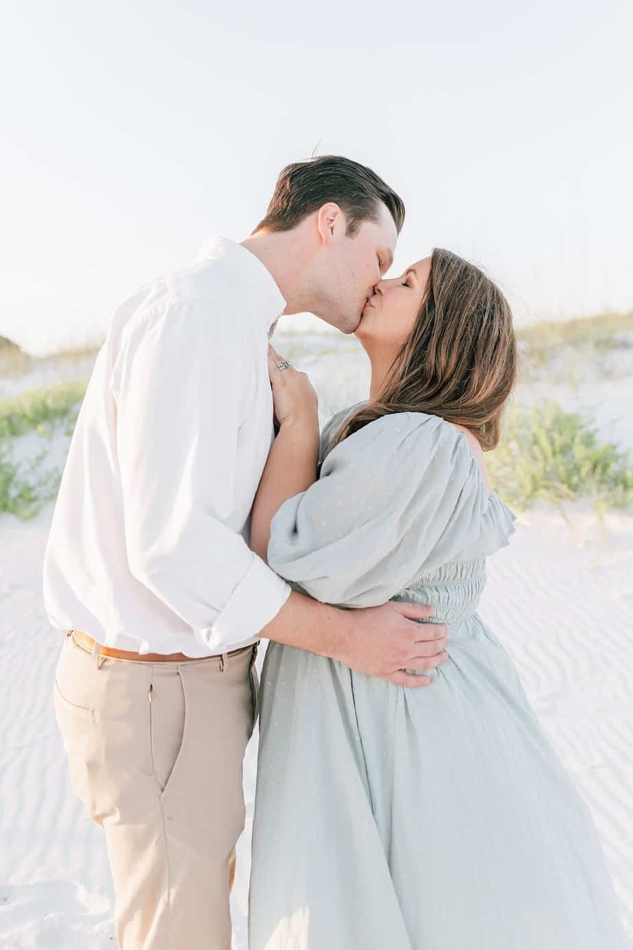man and woman kissing in the dunes of a destin beach in Florida