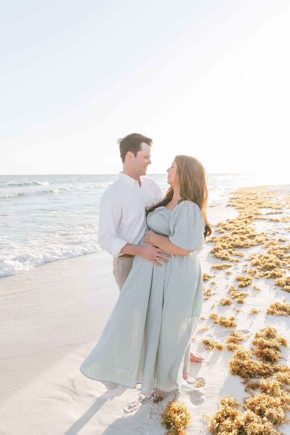 pregnant woman and man smiling at each other at Destin florida beach
