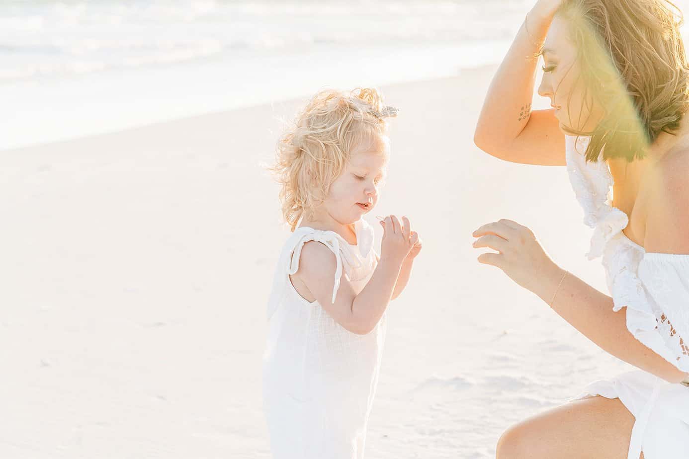 a mom and her little girl playing in the sand