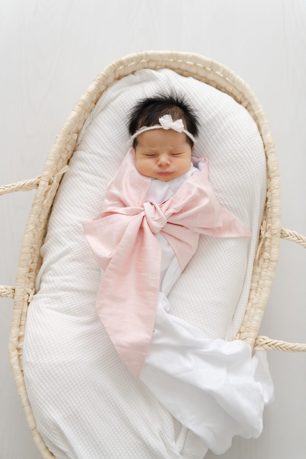 baby wrapped in a pink blanket in a moses basket