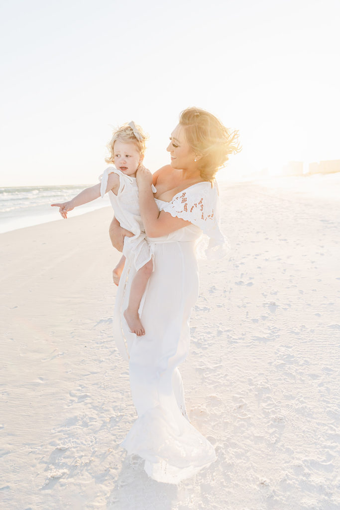 a mother dancing with her toddler on the beach