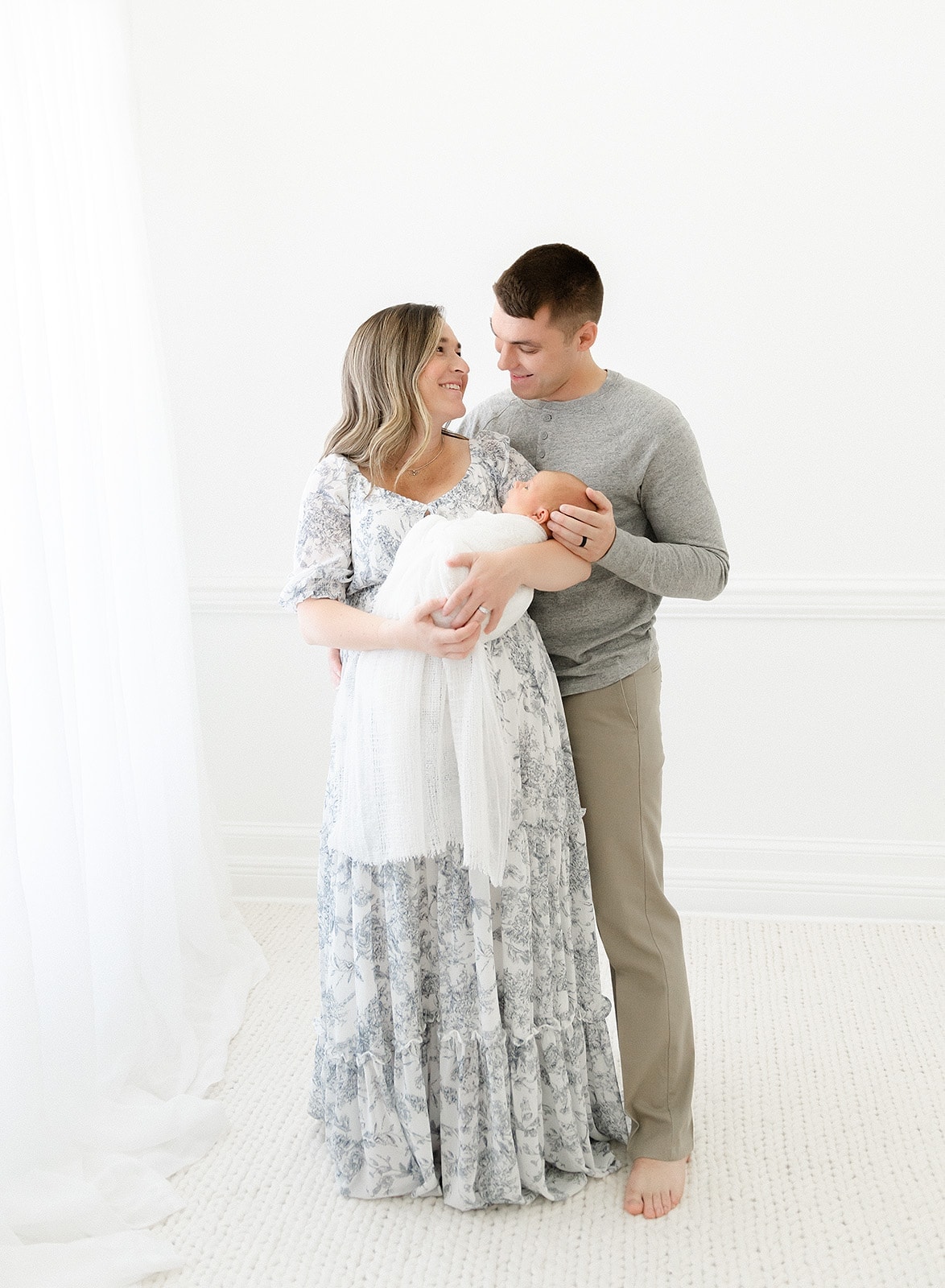 a woman and man looking at each other while holding a newborn at Tallahassee photographer