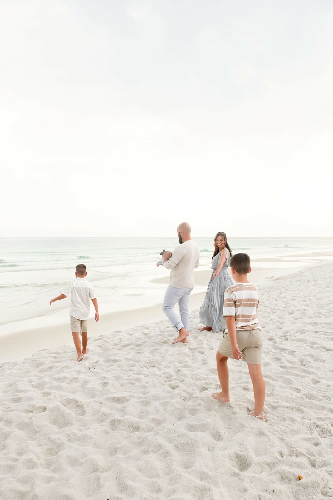 A family is playing on the beach with their children.