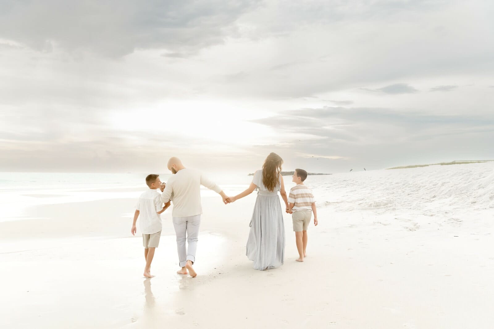 A family walking on the beach holding hands.