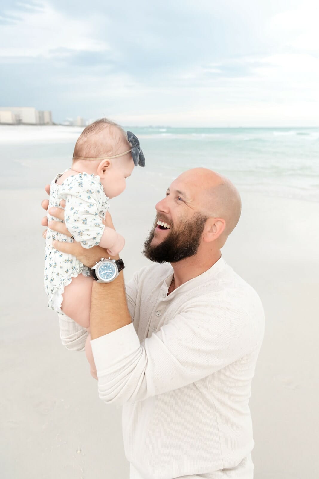 A man holding a baby on the beach.