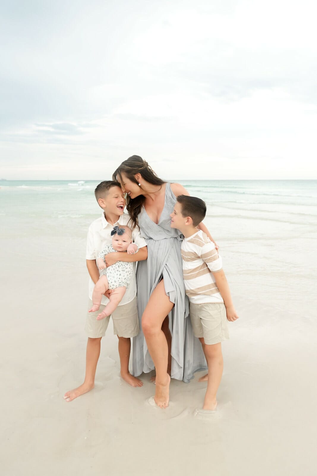 A family poses on the beach with their children.