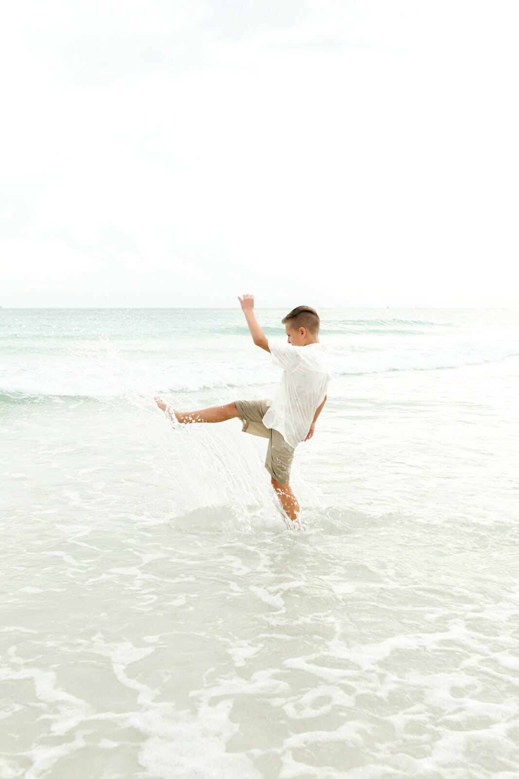 A boy kicking a ball in the ocean Destin Holiday Isle.