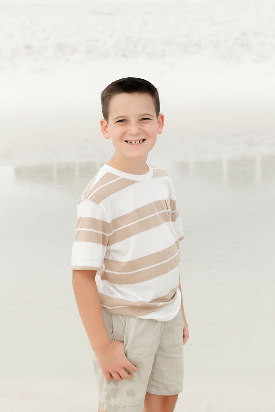 A boy in a striped shirt standing on the beach Destin Holiday Isle.