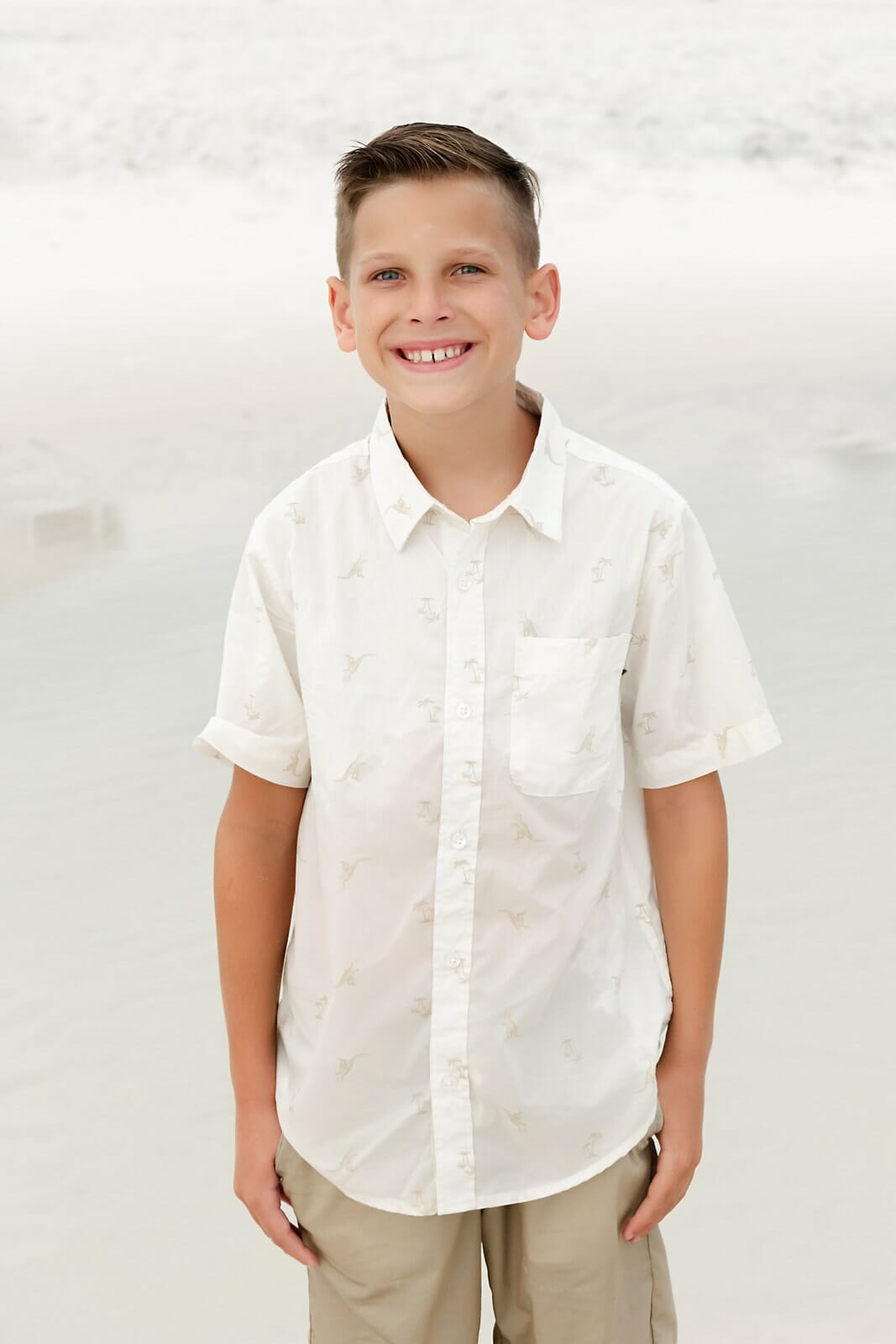 A young boy in a white shirt standing on the beach Destin Holiday Isle.