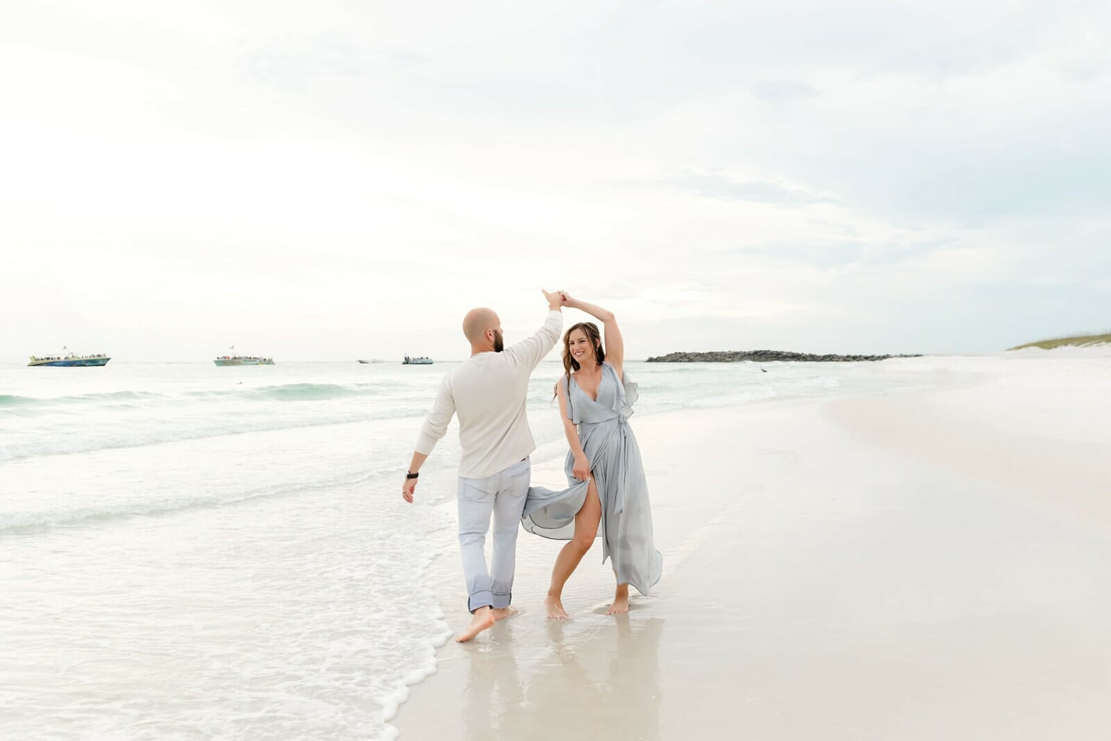 A couple dances on the beach holding hands at Destin Holiday Isle.