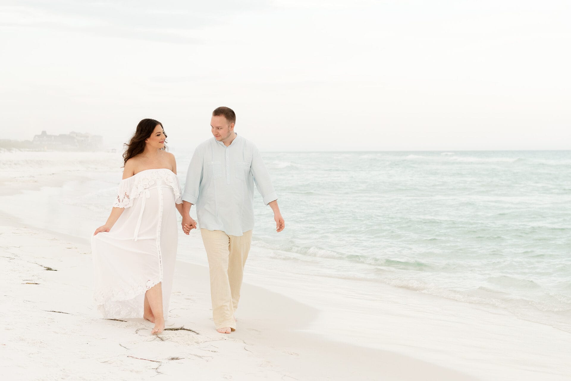A couple strolling along the sandy beach, tightly grasping each other's hands, enjoying the picturesque scenery of Destin, FL.