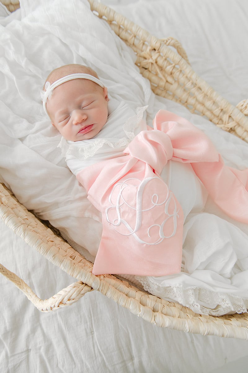 Sleeping newborn baby girl in a pink monogrammed swaddle with a bow, photographed by a Fort Walton Beach newborn photographer at Andrea Krey Photography