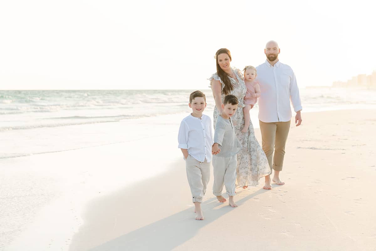 Family of five walking toward the camera along Henderson Beach during a Destin family photography session at golden hour