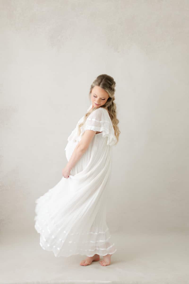 Maternity session timing: expecting mama in a flowing white gown at a Niceville studio session