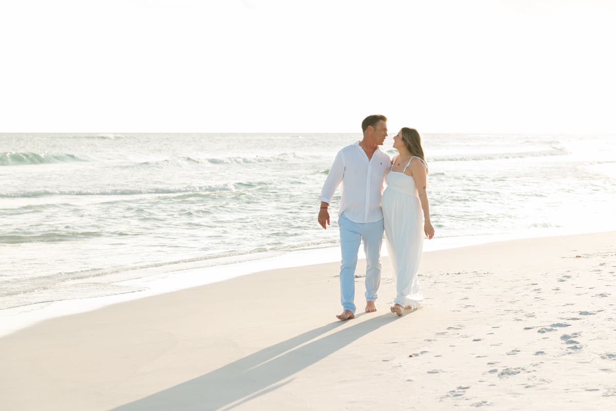 Couple walking along the Destin beach during a sunset maternity session