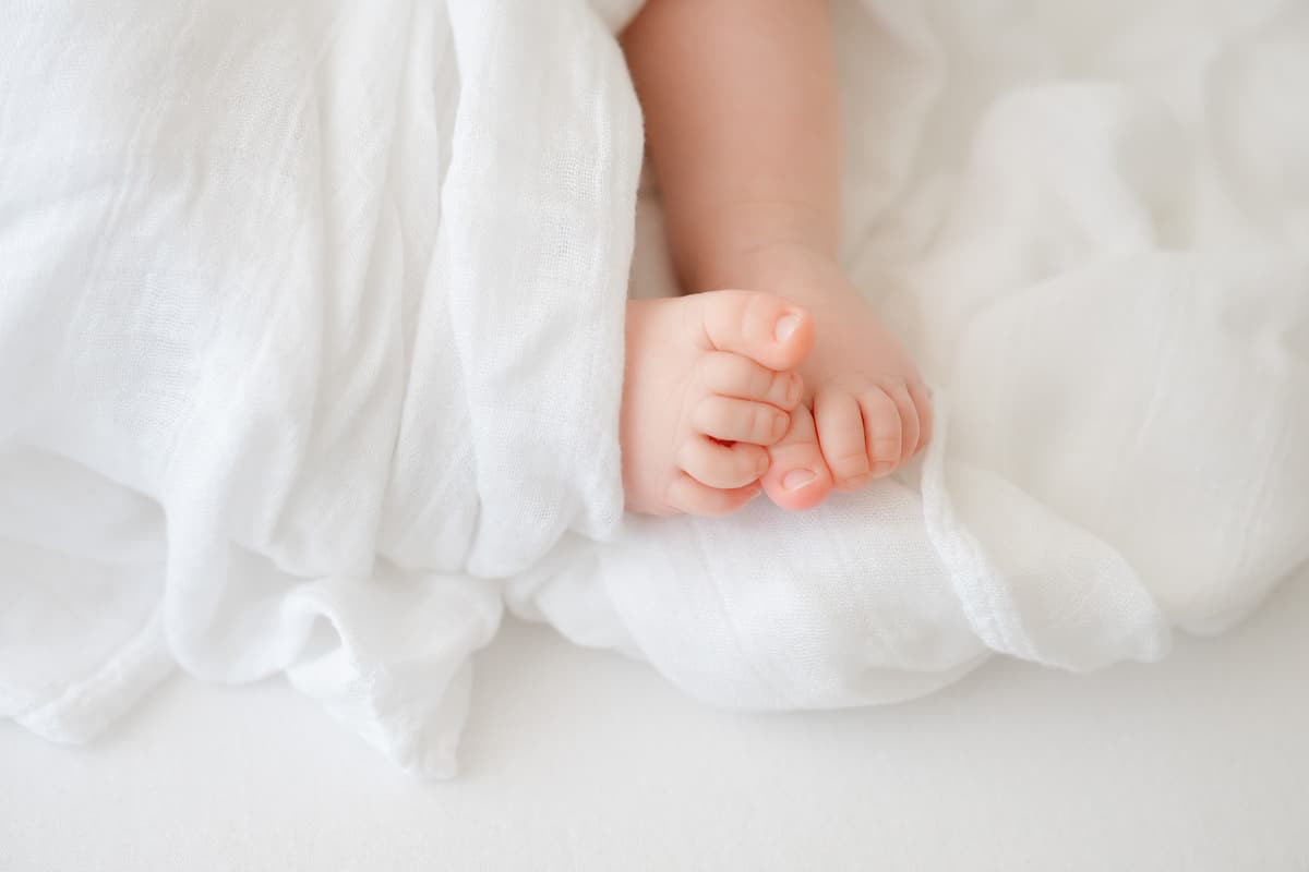 Tiny newborn toes peeking from a white wrap during an Emerald Coast newborn photography session