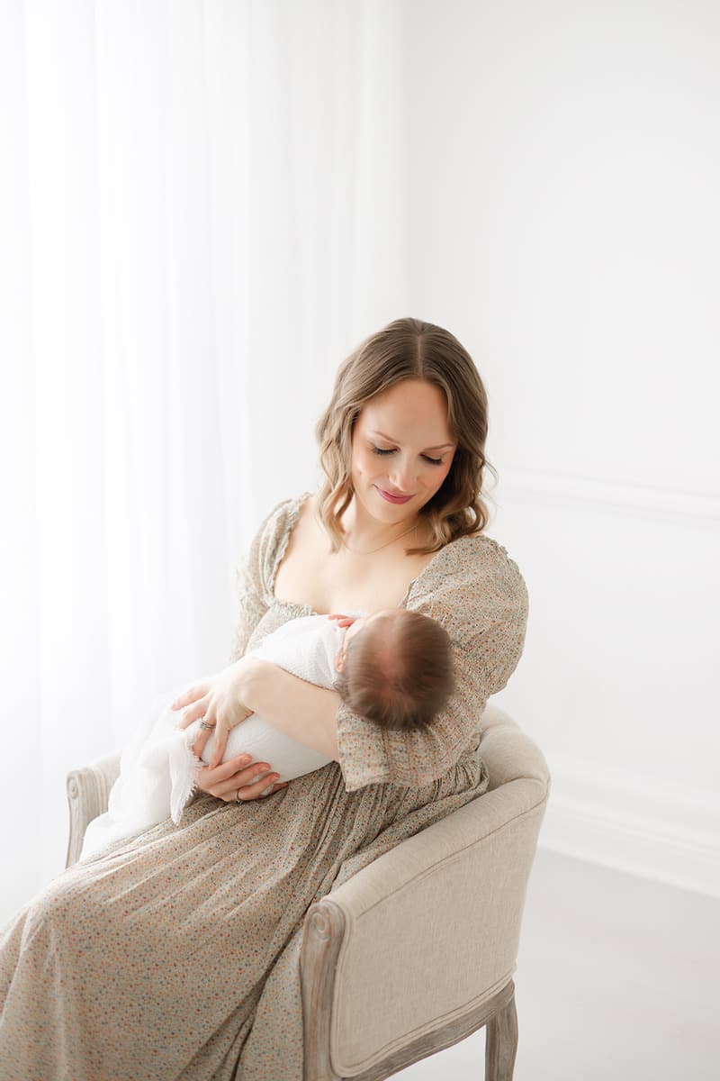 Mom nursing her newborn in soft natural light captured by an Emerald Coast newborn photographer