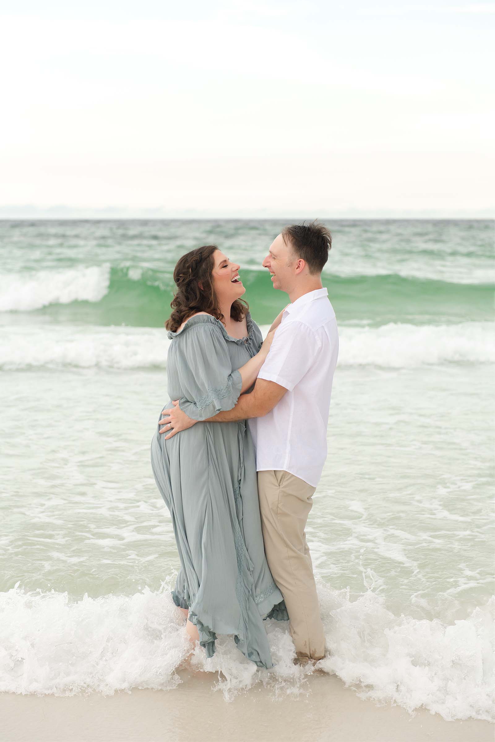 Couple laughing together in the ocean waves on a Destin beach, photographed by a Miramar Beach Florida photographer