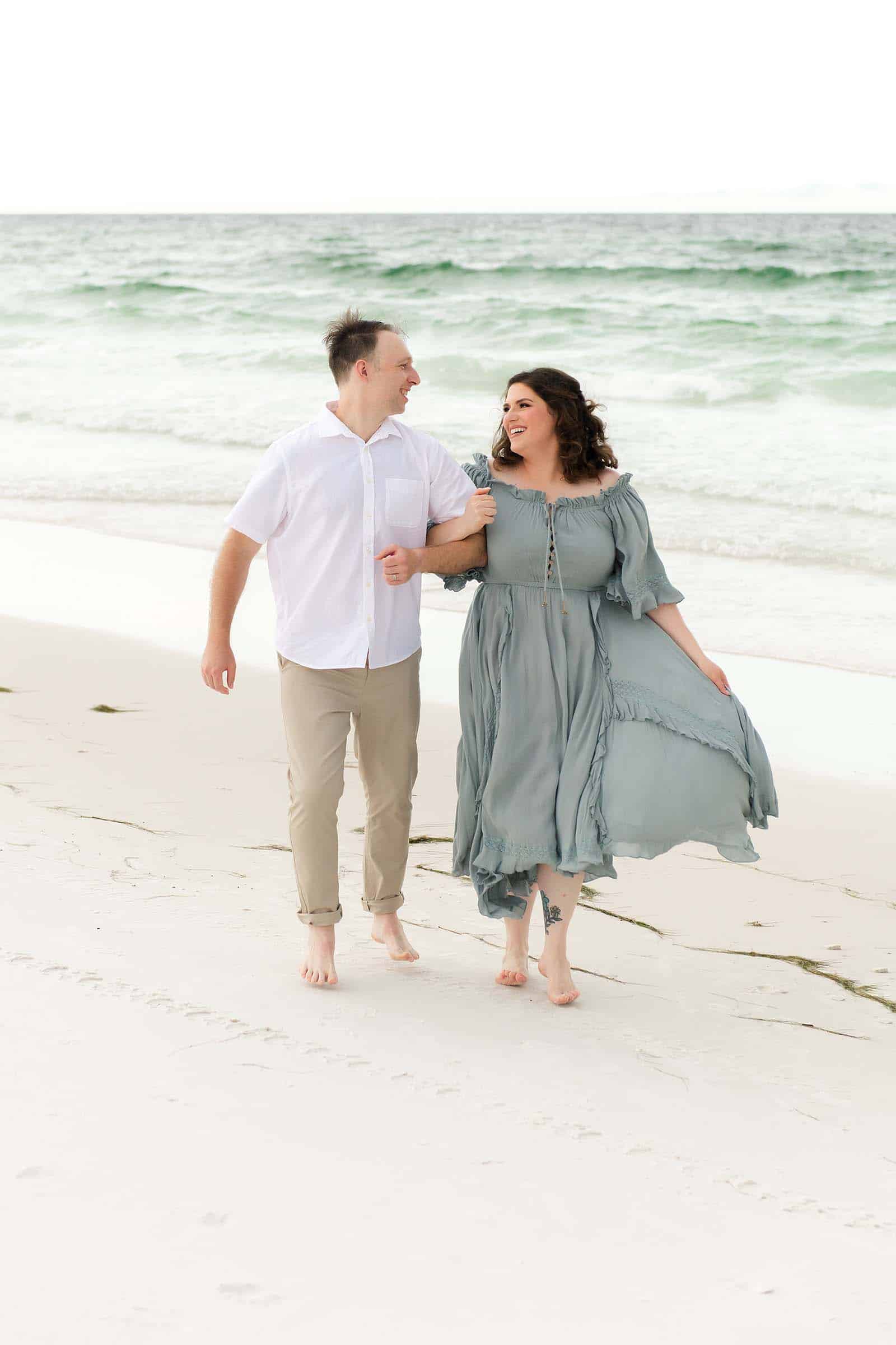 Couple walking arm in arm on a Destin beach, laughing together, photographed by a Miramar Beach Florida photographer