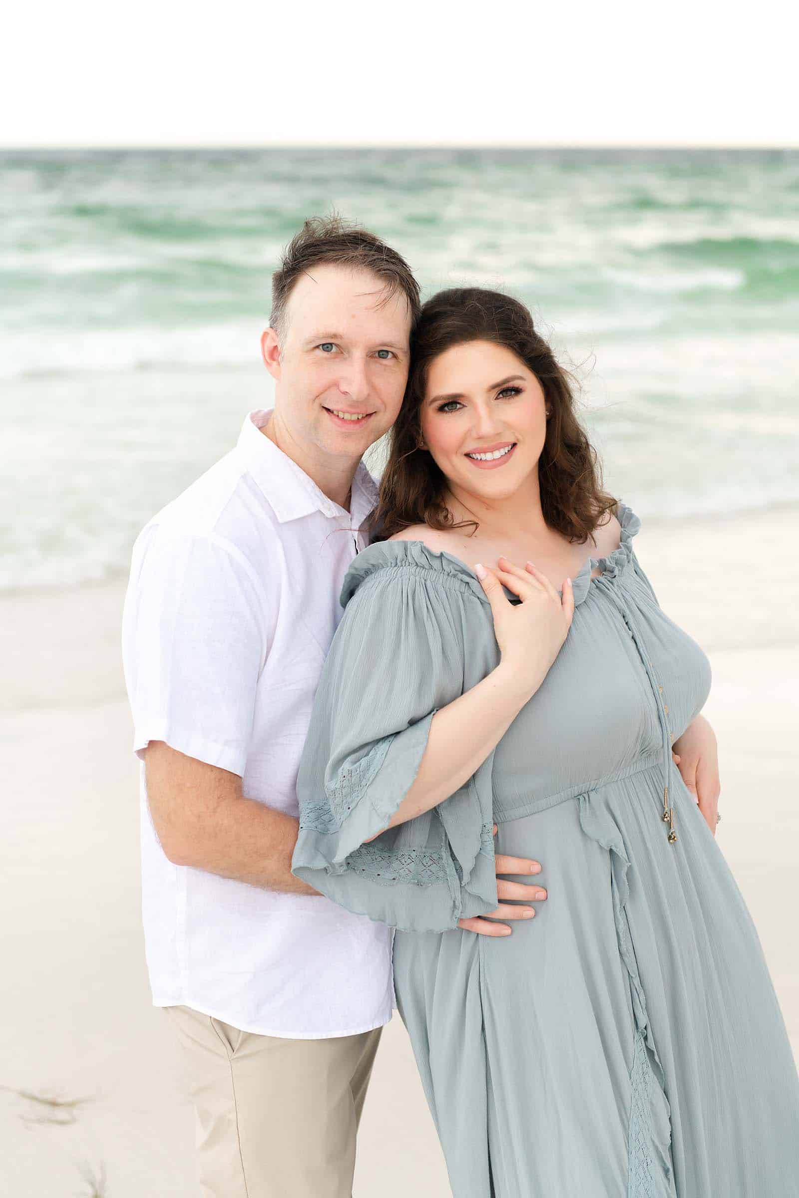 Husband and wife smiling together at the camera on a Destin beach, photographed by a Miramar Beach family photographer