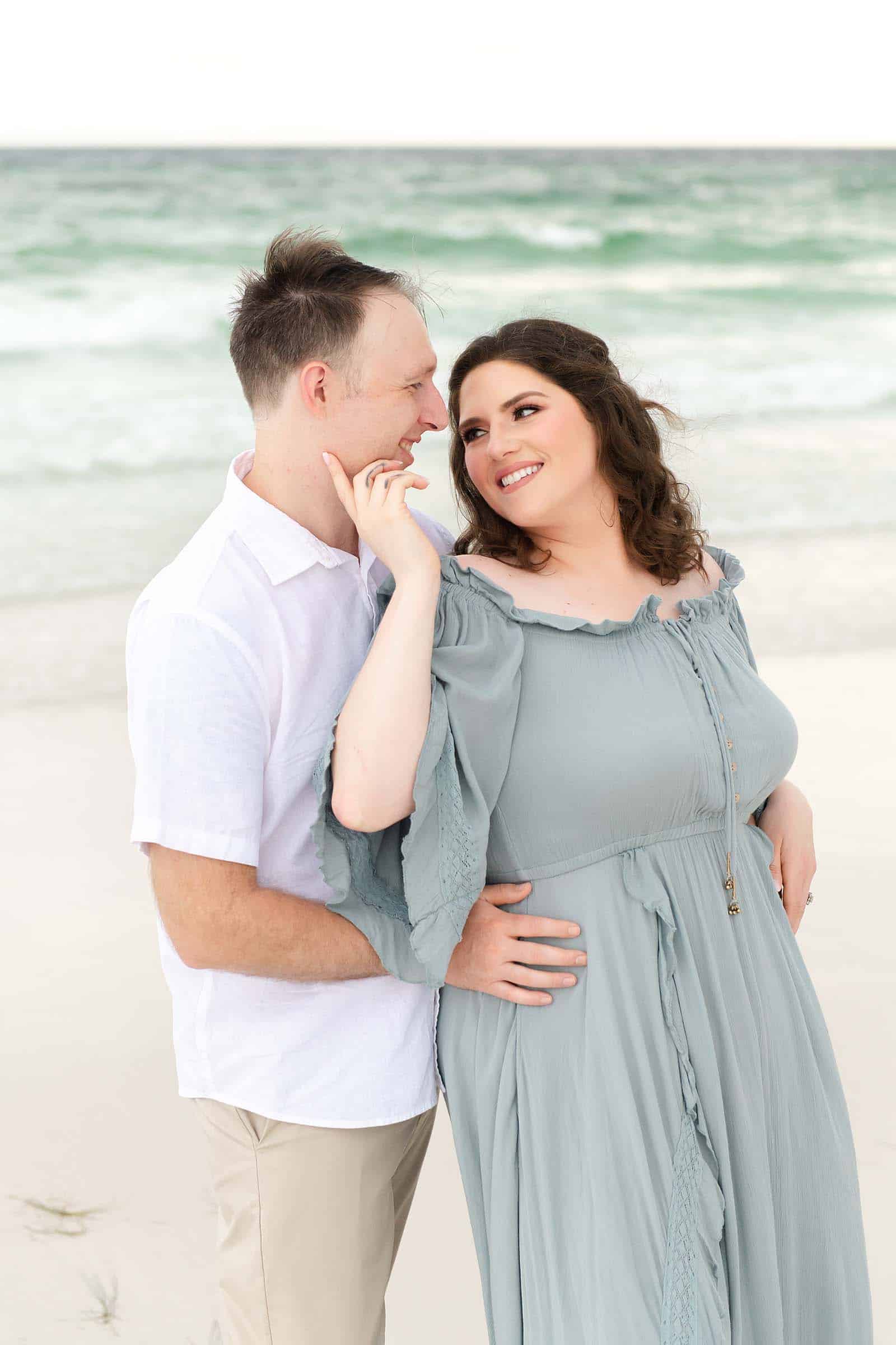 Wife touching her husband's face while they look at each other on a Destin beach, captured by a Miramar Beach photographer