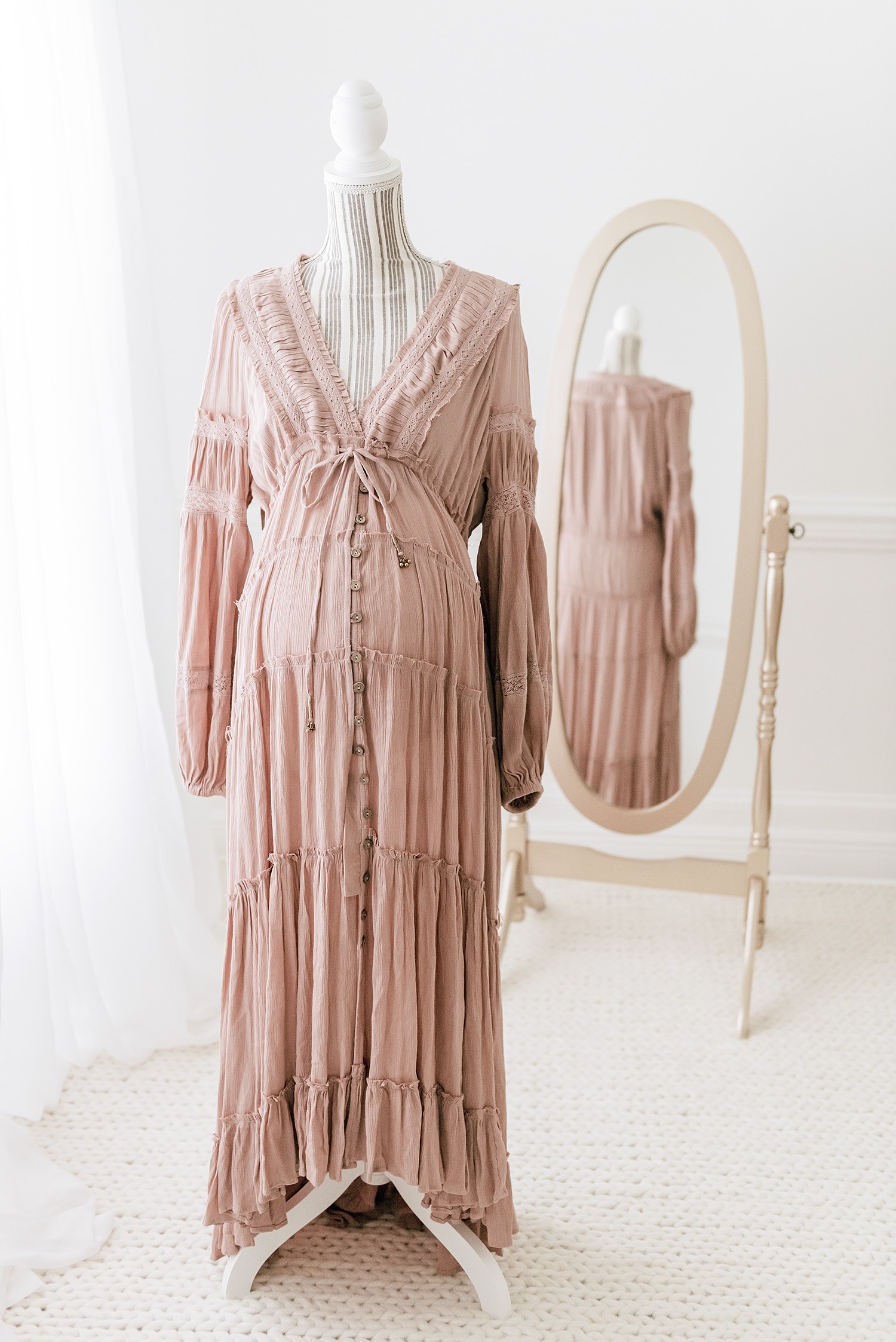 Blush dusty rose tiered maternity gown with V-neckline and ruffle details on dress form, representing warm muted tone palette for what to wear maternity photos Destin beach