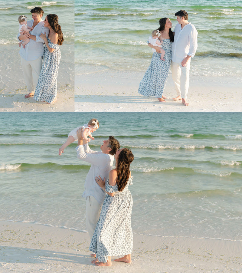 A couple with a baby enjoys fall family photos in Destin, walking by the water and looking lovingly at each other.