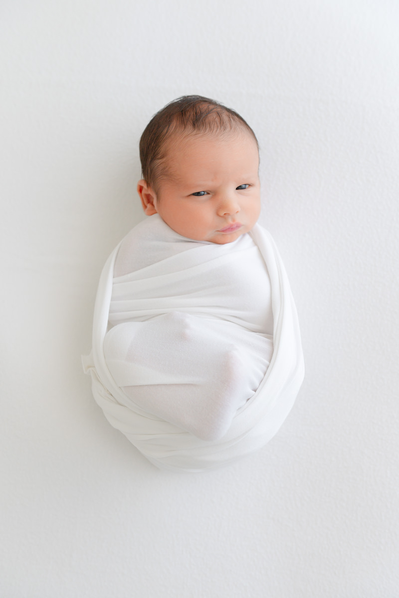 A newborn baby wrapped in a white swaddle, photographed by a Shalimar newborn photographer.