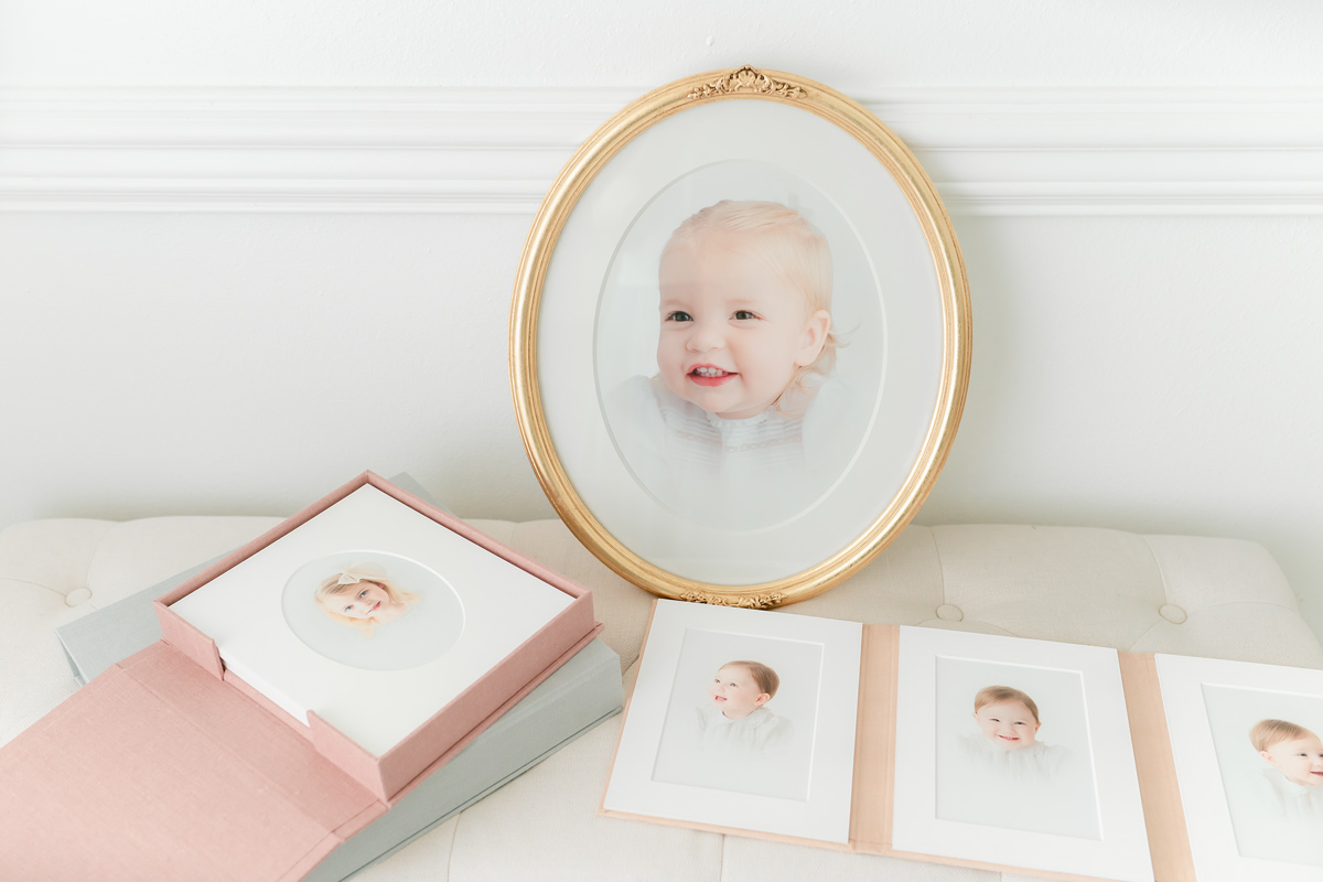 Framed portrait gift for grandparents, an oval gold frame, a pink print box and a folio of baby portraits
